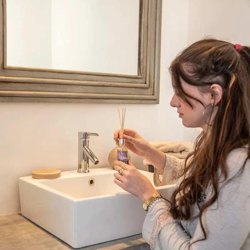 Mujer usando un difusor de varitas Eleka en el baño